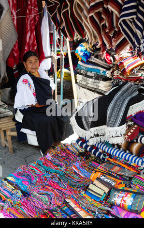 Textile stall und indigene Frau Standbesitzer; Otavalo Markt Ecuador Südamerika Stockfoto