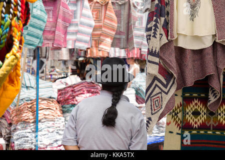 Indigene Mann mit Hut und mit pferdeschwanz als Inhaber Stall am Marktstand, Otavalo, Ecuador Südamerika Stockfoto