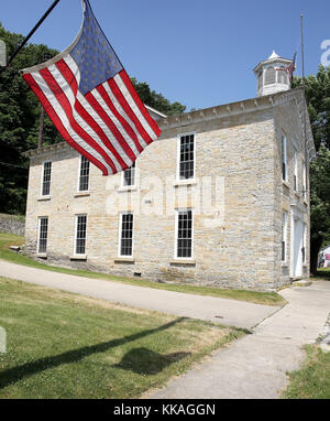 Iowa, USA. Juni 2017. Die Clayton School ist ein historisches Gebäude in Clayton, Iowa. Die zweistöckige Struktur, bestehend aus einheimischen Kalkstein, spiegelt den Wohlstand der Mitte des 19. Jahrhunderts, als es gebaut wurde. Es diente als Schulgebäude in das Ende des 20. Jahrhunderts, als der Bezirk mit einem benachbarten Schulbezirk konsolidiert, weil der Einschreibung rückläufig. Das Gebäude diente als Rathaus und Gemeindezentrum. Das 1860 fertiggestellte rechteckige Gebäude verfügt über eingehauene Dachrinnen und ein Giebeldach, das mit Dachgauben und einer achteckigen Kuppel bedeckt ist. Es war LIS Stockfoto