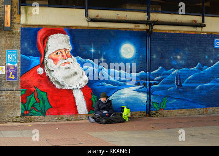 Obdachloser in Southend on Sea, die eingebrannte Obdachlosen-on-Sea. Rough sleeper, die in der Nähe von Frost neben Santa Claus street art Stockfoto