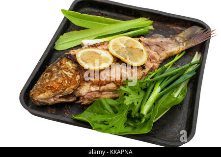 Gebackene Karpfen in Zitronensaft und Gewürzen mit grünem Salat mariniert auf einer Metallplatte. Auf einem weißen Hintergrund. Stockfoto