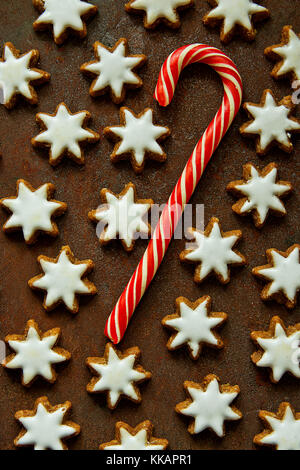 Traditionelle deutsche Weihnachtsplätzchen selbst gebackene verglaste Zimtsterne mit Muttern Zuckerstange Muster auf rostigen dunklen Hintergrund. festliche magische Atmosphäre Stockfoto