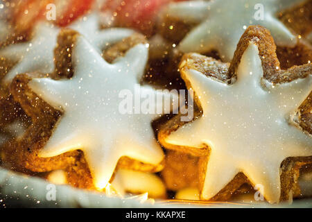 Traditionelle deutsche Weihnachtsplätzchen selbst gebackene verglaste Zimt Sterne in Weidenkorb Sekt Girlande lichter Kerze Zuckerstangen festliche Magic atmos Stockfoto