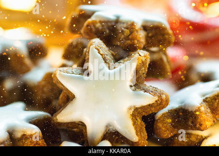 Stapel von traditionellen deutschen Weihnachtsplätzchen selbst gebackene verglaste Zimt Sterne funkelnde Girlande lichter Kerze Zuckerstangen festliche magische Atmosphäre Stockfoto