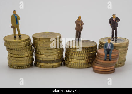 Miniatur Leute sitzen auf Münzen stapeln. auf weißem Hintergrund. Stockfoto