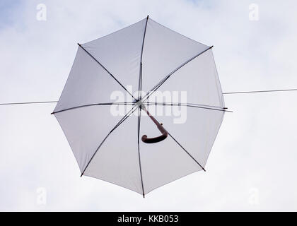 Weißer Regenschirm hängt draußen an Drähten, Odense Street Denmark Stockfoto