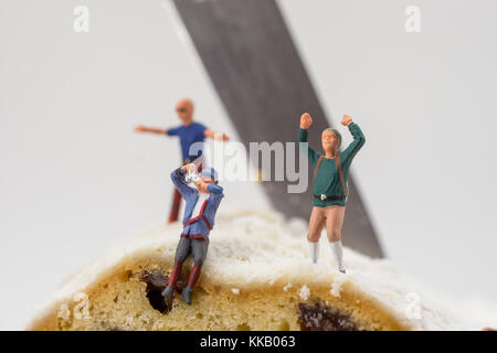 Miniatur Spielzeug Kletterer mit Kuchen und Rosinen Stockfoto