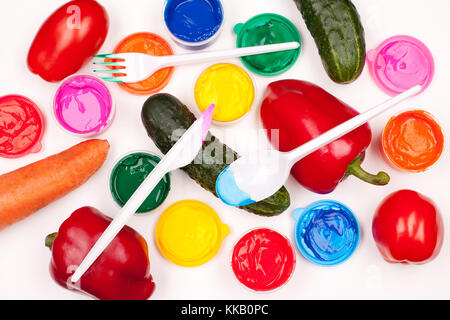 Bunte Farben, Gemüse (Tomaten, Gurken, Paprika, Karotte) und Kunststoff Gabel, Messer und Löffel auf dem weißen Hintergrund. studio Shot Stockfoto