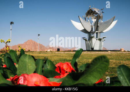 Sharm el Sheikh, Sinai, Ägypten - November 12, 2017: Monument, Platz des Friedens auf dem Hintergrund der roten Blumen Stockfoto