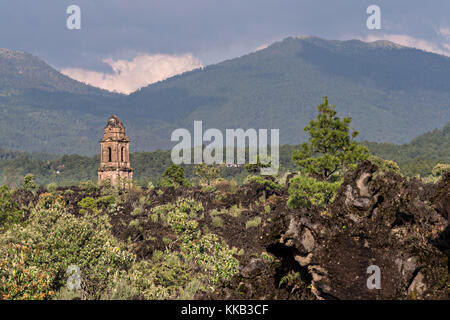 Der Turm der Kirche San Juan Parangaricutiro ragt aus einem Meer aus getrocknetem Lavagestein im abgelegenen Dorf San Juan Parangaricutiro, Michoacan, Mexiko, hervor. Diese Kirche ist die einzige noch verbliebene Struktur, die beim achtjährigen Ausbruch des Vulkans Paricutin begraben wurde, der 1943 zwei Dörfer verzehrte und die Region mit Lava und Asche bedeckte. Stockfoto