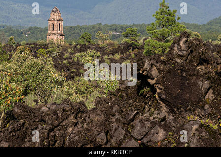 Der Turm der Kirche San Juan Parangaricutiro ragt aus einem Meer aus getrocknetem Lavagestein im abgelegenen Dorf San Juan Parangaricutiro, Michoacan, Mexiko, hervor. Diese Kirche ist die einzige noch verbliebene Struktur, die beim achtjährigen Ausbruch des Vulkans Paricutin begraben wurde, der 1943 zwei Dörfer verzehrte und die Region mit Lava und Asche bedeckte. Stockfoto