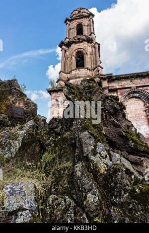 Der Turm der Kirche San Juan Parangaricutiro ragt aus einem Meer aus getrocknetem Lavagestein im abgelegenen Dorf San Juan Parangaricutiro, Michoacan, Mexiko, hervor. Diese Kirche ist die einzige noch verbliebene Struktur, die beim achtjährigen Ausbruch des Vulkans Paricutin begraben wurde, der 1943 zwei Dörfer verzehrte und die Region mit Lava und Asche bedeckte. Stockfoto