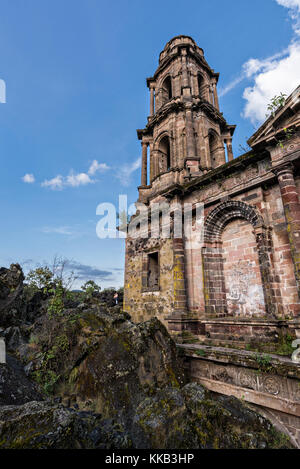 Der Turm der Kirche San Juan Parangaricutiro ragt aus einem Meer aus getrocknetem Lavagestein im abgelegenen Dorf San Juan Parangaricutiro, Michoacan, Mexiko, hervor. Diese Kirche ist die einzige noch verbliebene Struktur, die beim achtjährigen Ausbruch des Vulkans Paricutin begraben wurde, der 1943 zwei Dörfer verzehrte und die Region mit Lava und Asche bedeckte. Stockfoto