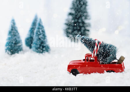 1950 antique Vintage red Lkw schleppen einen Weihnachtsbaum nach Hause durch einen verschneiten Winter Wonder Land. Extrem flache Tiefenschärfe mit selektiven Fokus Stockfoto