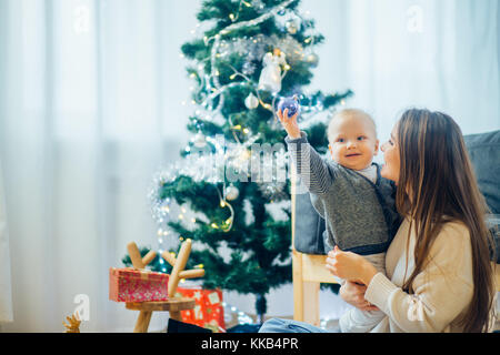 Glückliche Mutter Übersicht christmas ball Baby in der Nähe von Christbaum Stockfoto