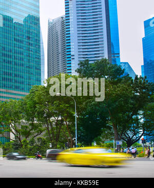 Autos, die sich schnell bewegen, überqueren die Straße in Singapore Downtown. Bewegungsunschärfe Stockfoto