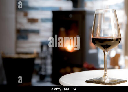Glas Rotwein und Feuer im Herd - romantisches Wohnzimmer Landschaft Stockfoto
