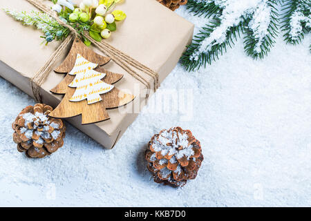 Weihnachten Rahmen mit Geschenk, die Zweige der Weihnachtsbaum und Holzdekorationen auf Schnee Hintergrund. Einfache weihnachten Zusammensetzung Stockfoto