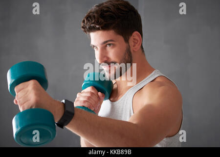 Schuss ein junger sportlicher Mann, Arbeit mit Gewichten in der Turnhalle. Stockfoto