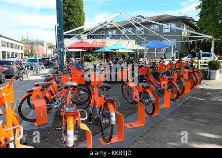 Orange Biketown Leihfahrräder am Parkplatz Bahnhof & Menschen essen im Freien an Tischen mit Lardo sandwich Restaurant in Portland, Oregon, USA KATHY DEWITT geparkt Stockfoto