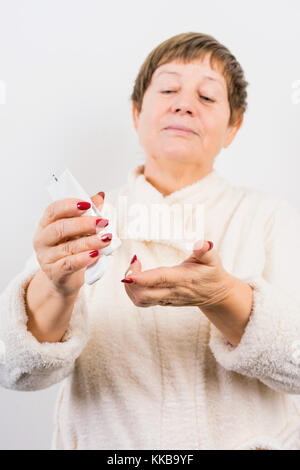 Grandma drückt eine Creme auf Händen Stockfoto