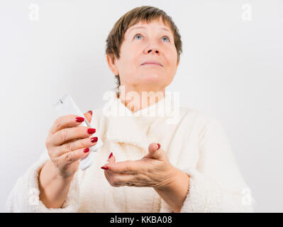 Grandma drückt eine Creme auf Händen Stockfoto