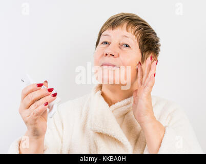 Grandma drückt eine Creme auf Händen Stockfoto