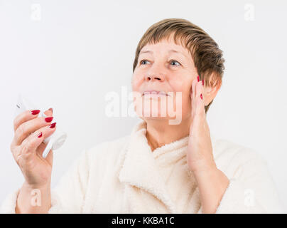 Grandma drückt eine Creme auf Händen Stockfoto