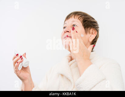 Grandma drückt eine Creme auf Händen Stockfoto