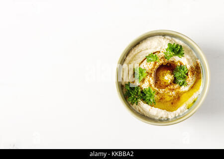 Vegetarische Snack. Hummus mit grünen, mit Olivenöl und Paprikapulver in einer Keramikplatte gekleidet. hellen weißen Hintergrund. traditionellen nahöstlichen cuisin Stockfoto