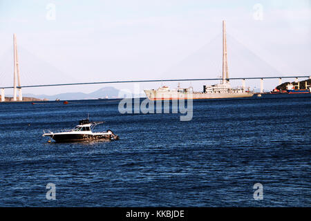 Russland, Wladiwostok, 27.09.20017. Blick auf goldenen Brücke in Wladiwostok Stadt mit einem Schiff und kleine Yacht in der Bucht. Stockfoto