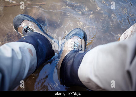 Mann, Wanderschuhe in einen Bach mit seinen Füßen untergetaucht im Wasser in eine First Person Sicht Stockfoto