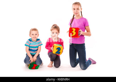 Happy Kids holding Bausteine mit Zahlen auf weißem Hintergrund. Teamwork Konzept. Stockfoto