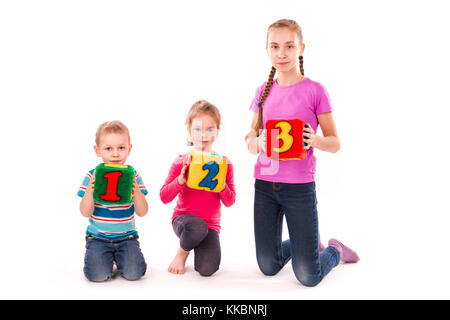 Happy Kids holding Bausteine mit Zahlen auf weißem Hintergrund. Teamwork Konzept. Stockfoto