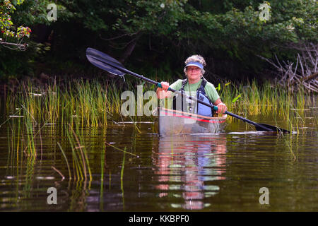 Reife Frau Paddeln in einem Kanu auf einem entfernten adirondacks See. Stockfoto