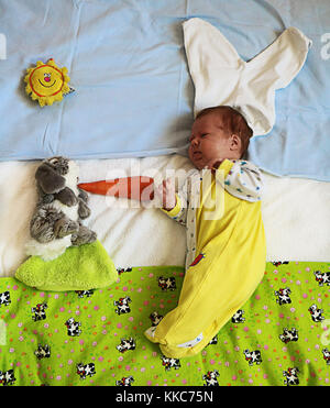 Cute Baby mit Hasenohren spielen mit Bunny toy Nährt es mit Karotte. Stockfoto