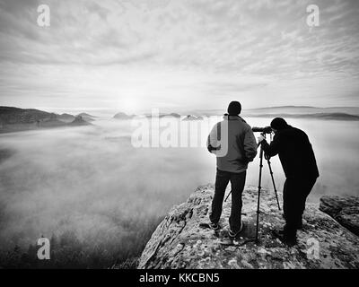 Silhouetten der Mann Fotografen. Männer auf Berg. Peak mit zwei Männern, die Fotos im Herbst Sonnenaufgang Stockfoto