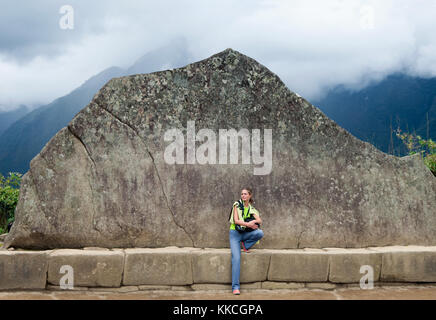 Junge Mädchen und Inka Wand in Machu Picchu. Beispiel für polygonale Mauerwerk. Die berühmten 32 Winkel Stein in der alten Inka Architektur. Beispiel für polygonale Stockfoto