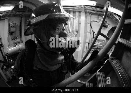 Der Mechanische Feuerwehrmann Isabel Chavez, der dem Arleigh-Raketenzerstörer der Burke-Klasse USS McCampbell DDG 85 zugeteilt wurde, leitet einen Feuerschlauch an Seeleute weiter, die während einer Schadenskontrollübung in Sea of Japan ein simuliertes Feuer bekämpfen. Bild mit freundlicher Genehmigung des Spezialisten für Massenkommunikation Seaman Declan Barnes/US Navy. 2012. Stockfoto