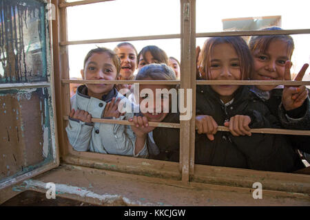 Die irakischen Studenten posieren für ein Foto durch eine Schule Fenster an einer Grundschule, Aski Mossul, Irak, Nov. 13, 2017. Die Breite und Vielfalt der Koalitionspartner zeigt die globalen und einheitlichen Ziel der Sieg über ISIS im Irak und in Syrien. Combined Joint Task Force - inhärenten Lösen, die globale Koalition zu besiegen ISIS im Irak und in Syrien. (U.S. Armee Foto von Sgt. Tracy McKithern) Stockfoto