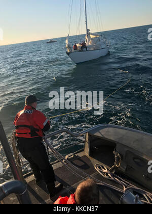 Coast Guard Seemanns John Warren, ein Crew Mitglied an der Coast Guard Station Hatteras Inlet, neigt der Linie beim Abschleppen eines Segelboot nehmen auf Wasser, 13 km östlich von Hatteras Island, North Carolina, November 26, 2017. Die Küstenwache 47-Fuß-Motor Life Boat Crew das Segelboot zu Oden's Dock auf Hatteras Island geschleppt. (U.S. Coast Guard Foto von Petty Officer 2. Klasse Chuck Seckinger/Freigegeben) Stockfoto