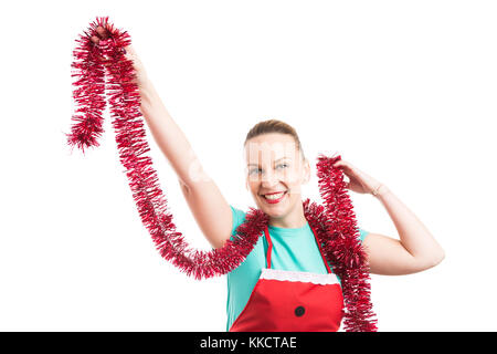 Glücklich lächelnde Frau oder Mädchen tanzen mit Weihnachten lametta Girlande tragen rote Schürze auf weißem Hintergrund Stockfoto