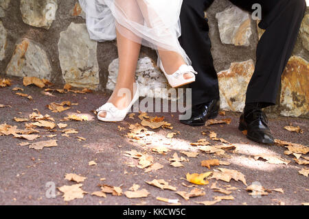 Füße der Bräutigam und die Braut sitzen in einem Park. Stockfoto