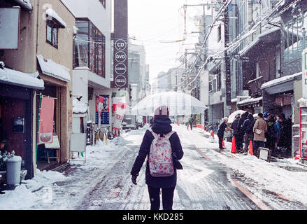 Mädchen mit Schirm und wandern durch verschneite Straße in Kyoto, Japan im Winter Stockfoto