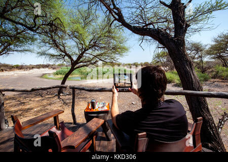 Mann mit Tablet auf Onguma Tree Top Camp onguma Game Reserve, Namibia, Afrika Stockfoto