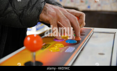 Mann, der alte Spielekonsole spielt. Joystick eines klassischen Arcade-Videospiels - Coin-OP. Nahaufnahme eines Mannes, der Arcade-Spiele mit dem Joystick auf dem alten Conso spielt Stockfoto