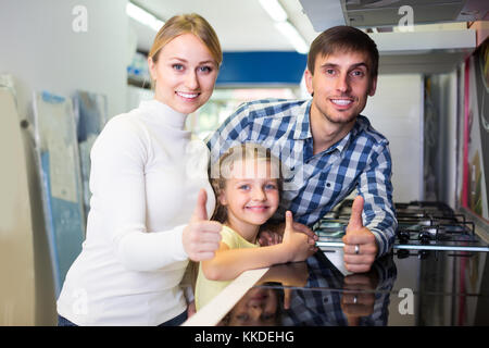 Portrait der freudigen Familie mit kleinen Tochter Auswahl Küche Herd im Gerät speichern. Im Mittelpunkt der Mensch Stockfoto