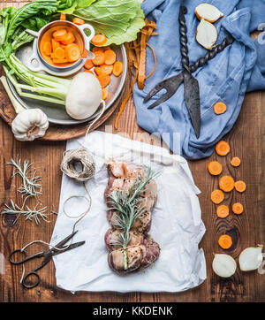 Kochen Vorbereitung von rohem Fleisch gebraten mit Gemüse und frische Würze aus rustikalem Holz- Hintergrund, Ansicht von oben. Land Küche Stockfoto