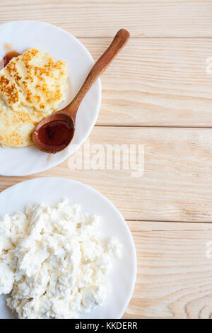 Zwei weiße Platten mit frischem Quark und Käsekuchen auf Holztisch mit kopieren. Ansicht von oben. Stockfoto