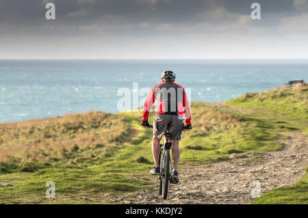 Mountainbiken - ein Radfahrer, Mountainbiker, ein Mountainbike über einen Fußweg auf der East Pentire Newquay Cornwall im Vereinigten Königreich. Stockfoto